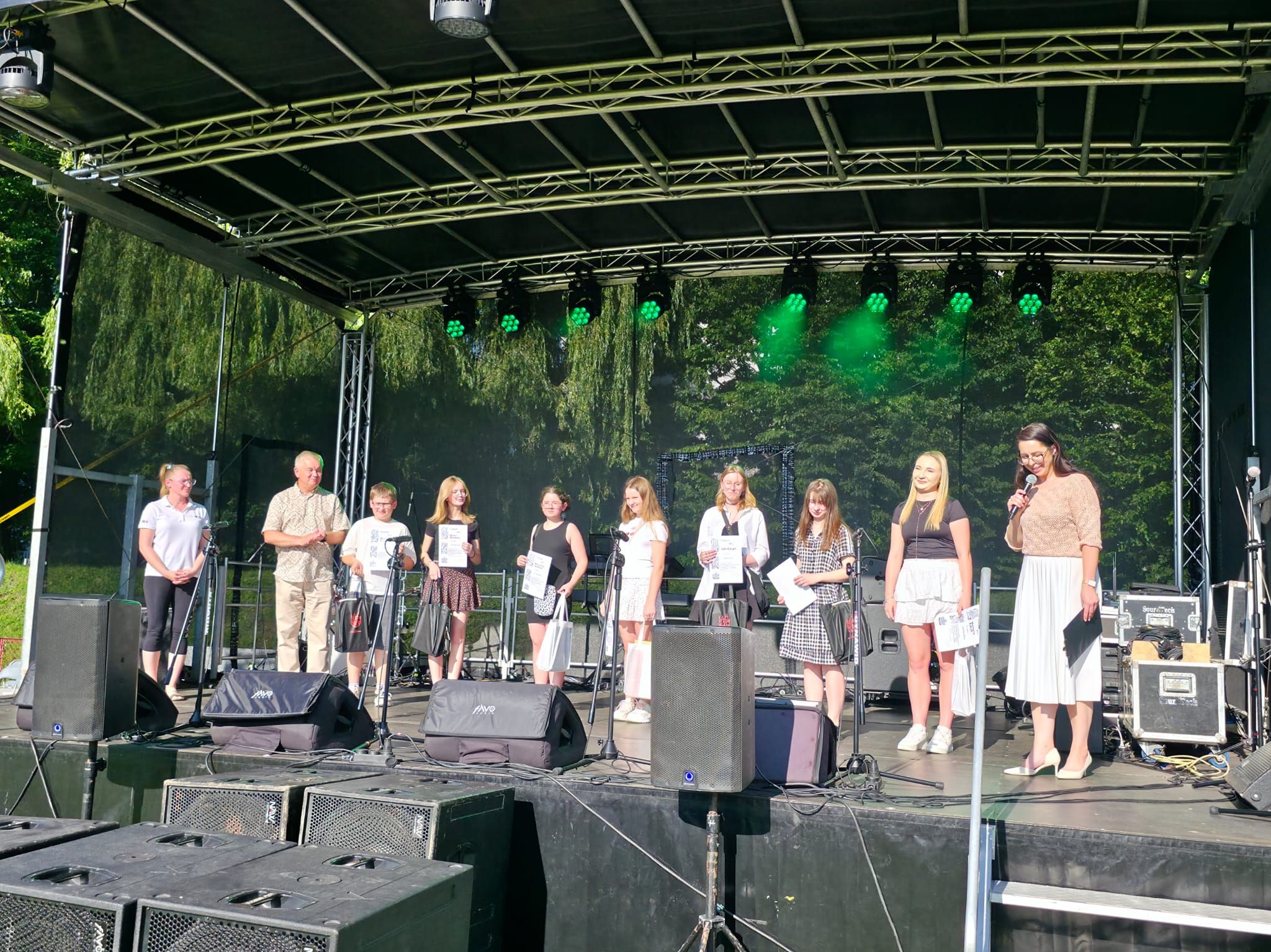 dzieci stoją na scenie i trzymają w rękach dyplomy