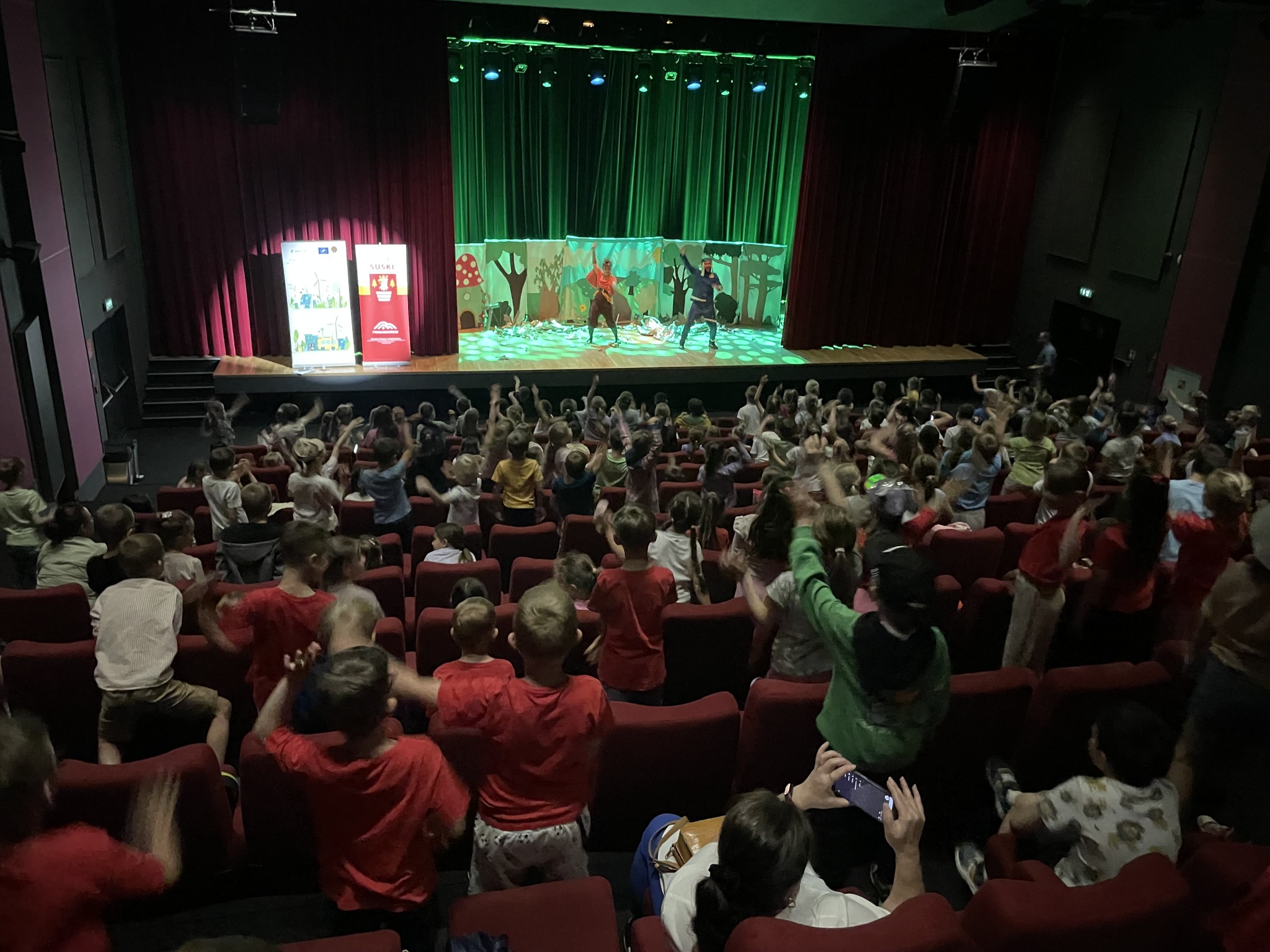 dzieci siedzą w sali kinowej oglądając spektakl