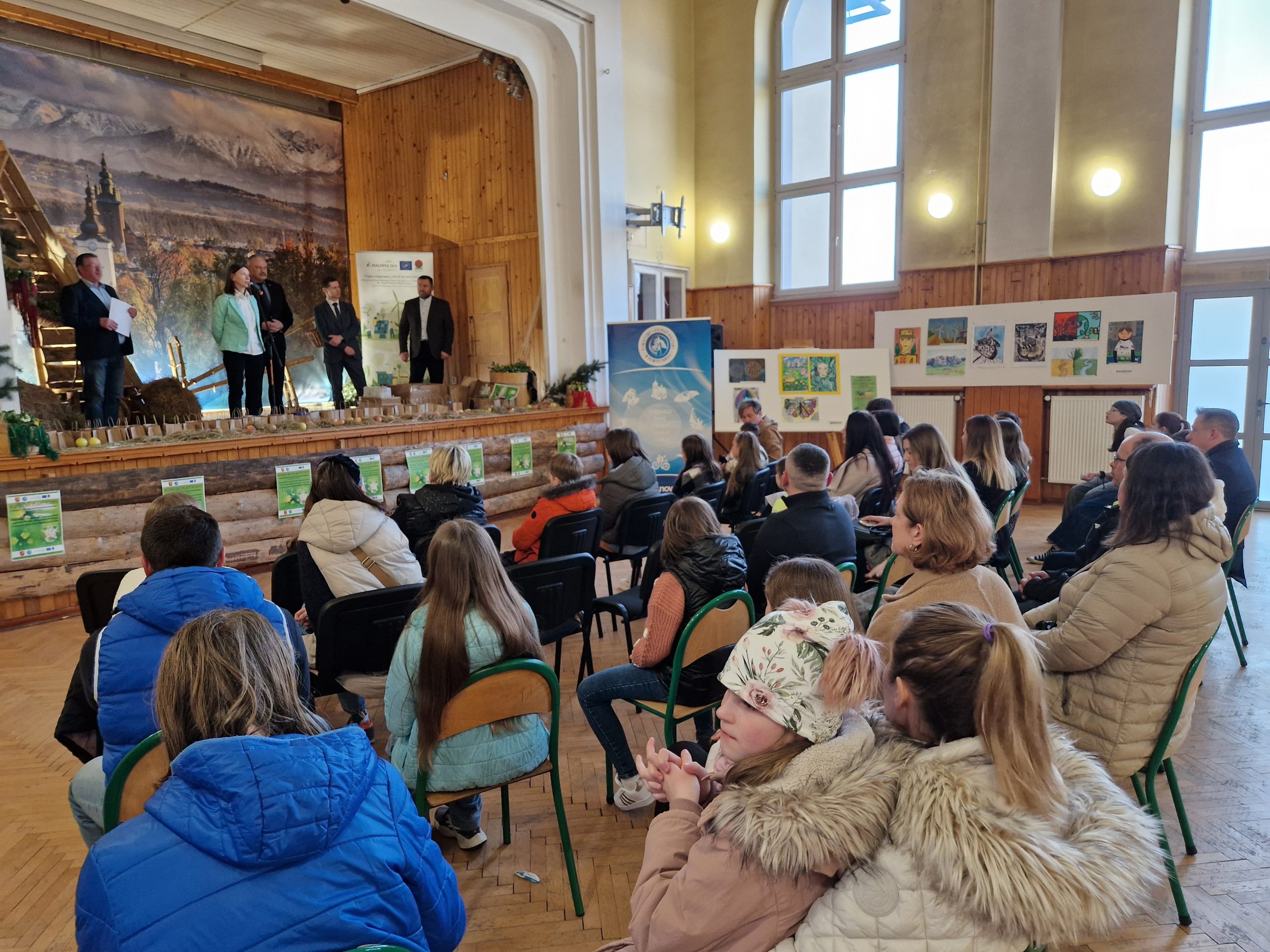 Dzieci na widowni a w tle prace plastyczne