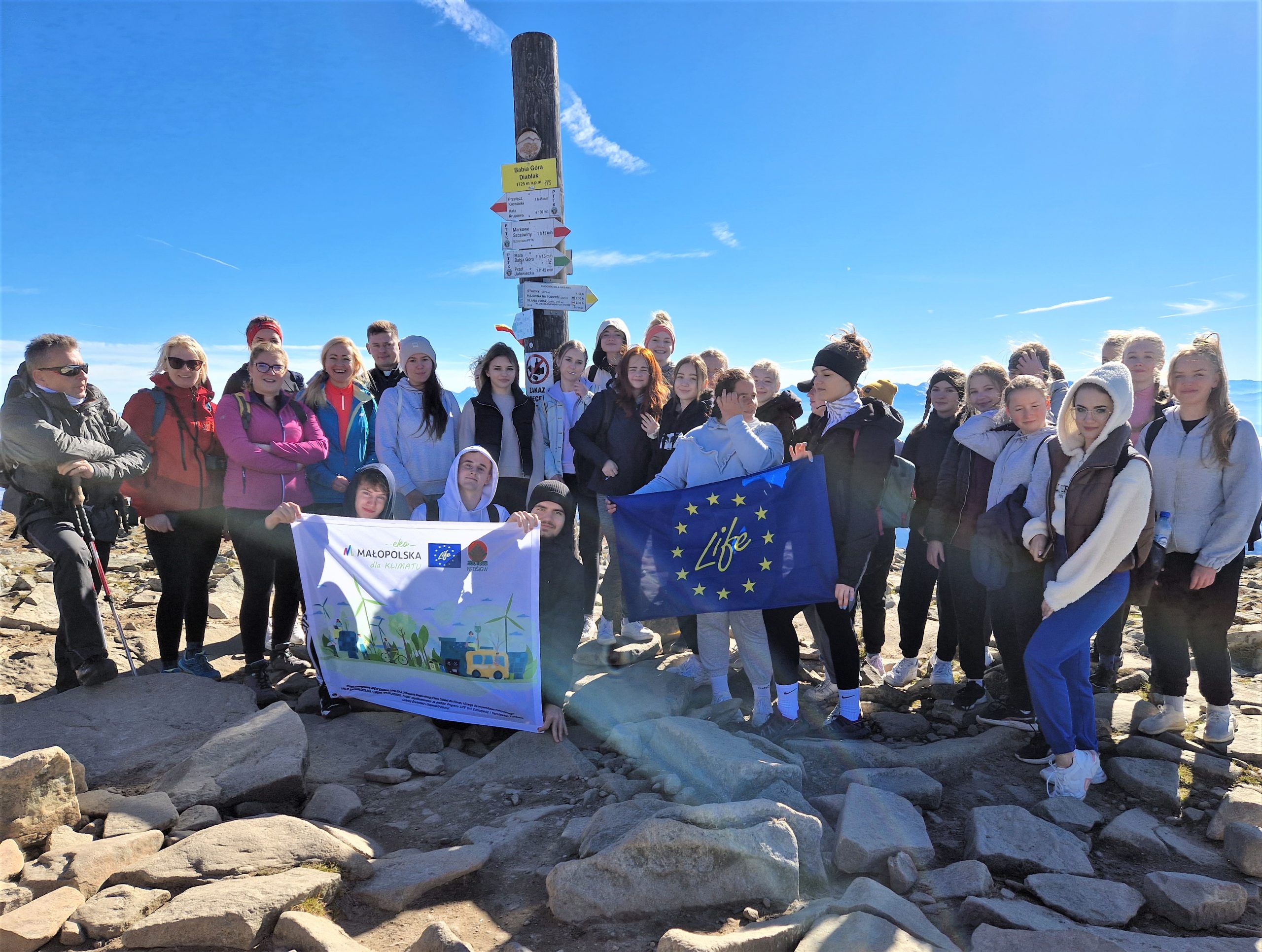 Grupa młodzieży z przewodnikiem i flagą LIFE