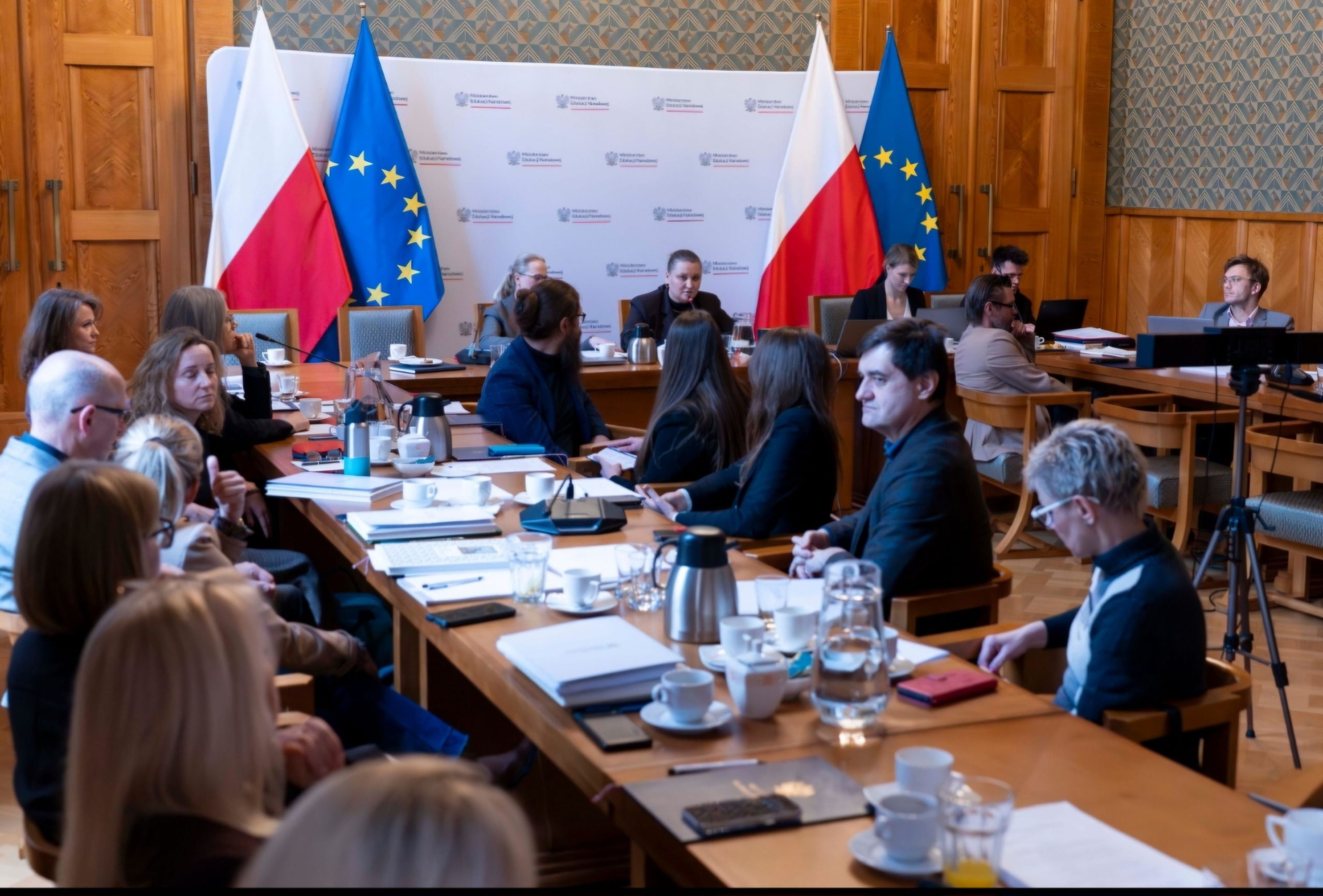 Grupa ;ludzi z ministerstwa edukacji siedzi przy stole w trakcie obrad