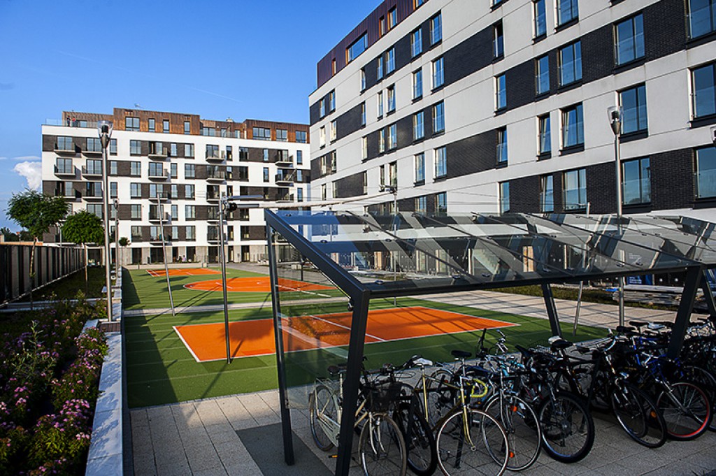 Zdjęcie przedstawia Osiedle Fi, na terenie którego znajdują się boiska i wiaty rowerowe