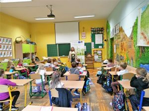 kobieta zatrudniona na stanowisku doradcy ds. klimatu i środowiska prowadzi wykład dla dzieci w szkole podstawowej
