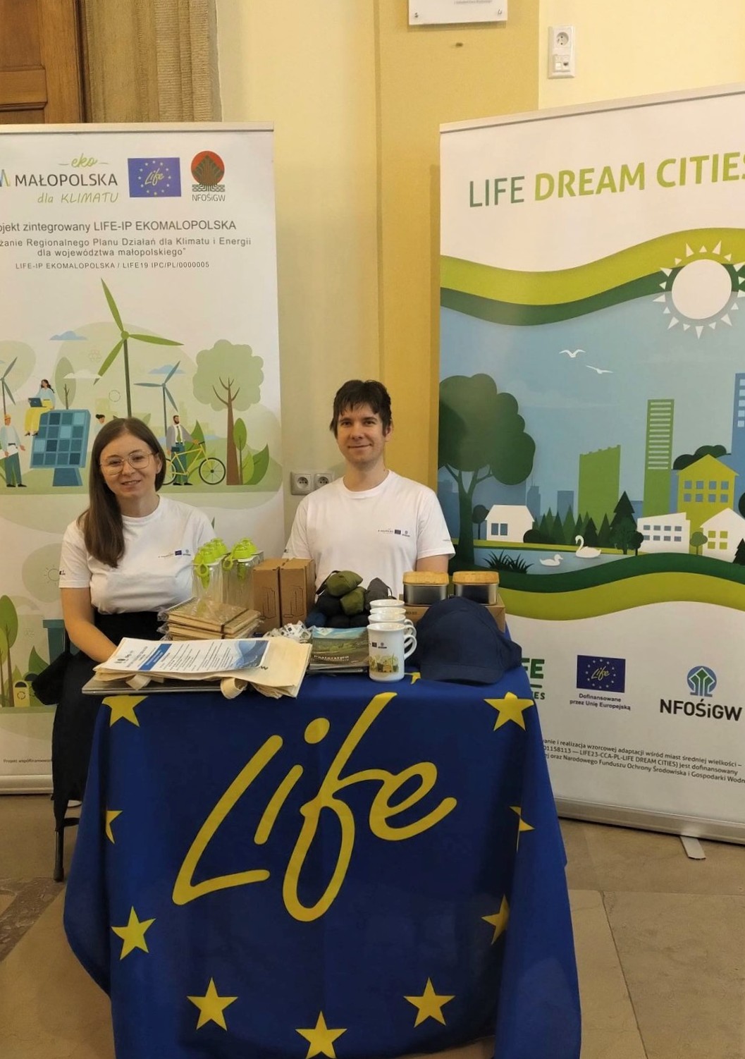 Dwie osoby na stolisku LIFE z gadżetami