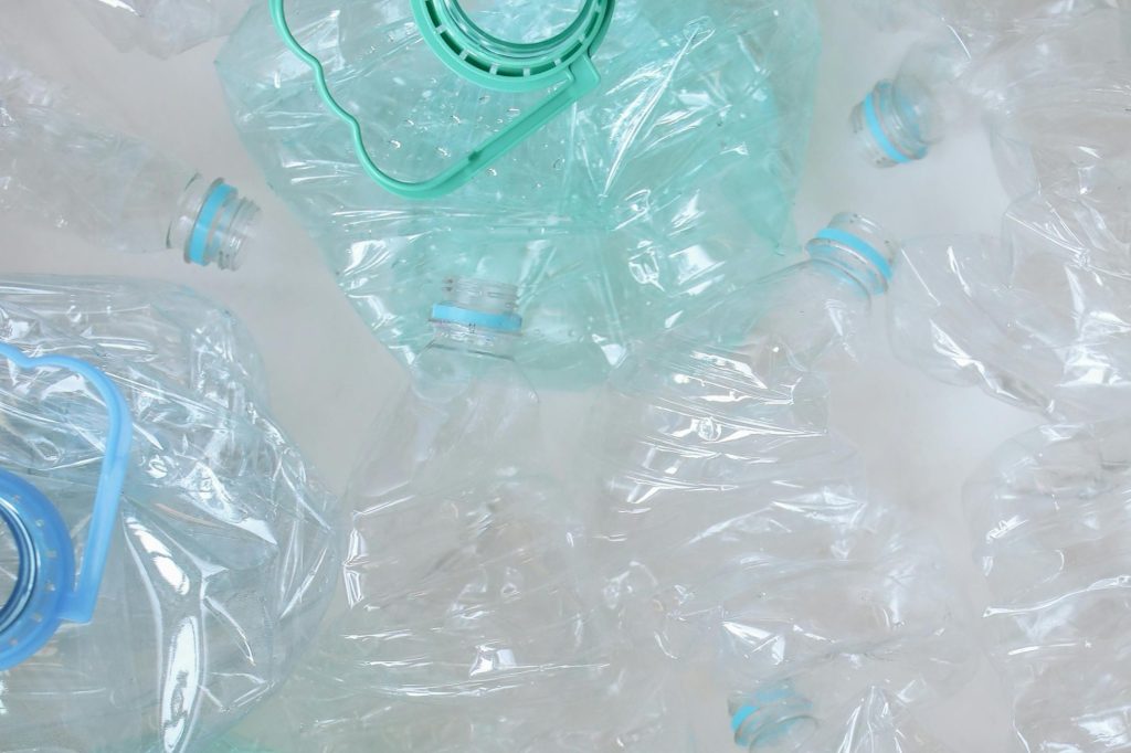 Zdjęcie przedstawia pogięte plastikowe butelki na białym tle