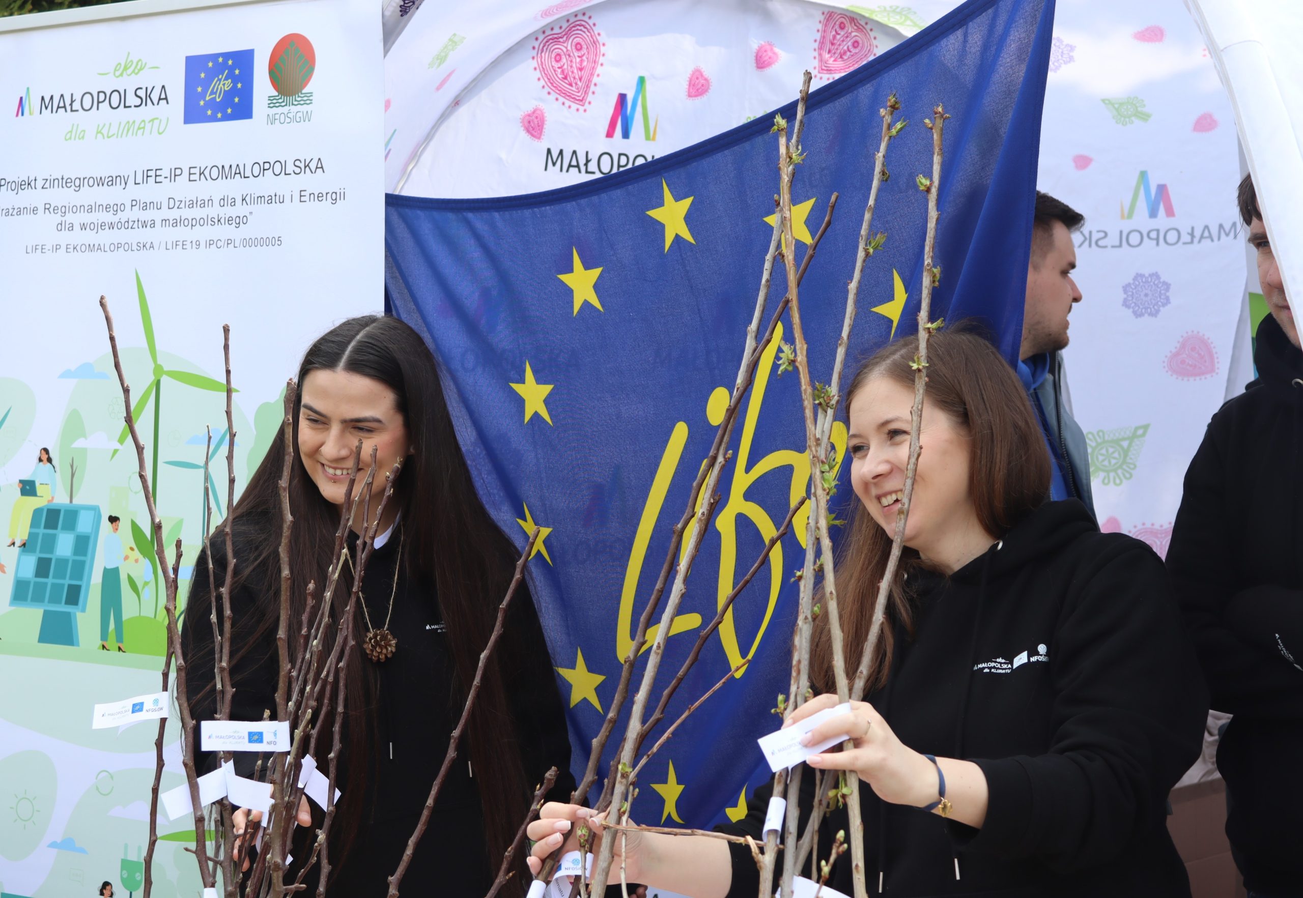 Dwie kobiety wręczają drzewka na stoisku