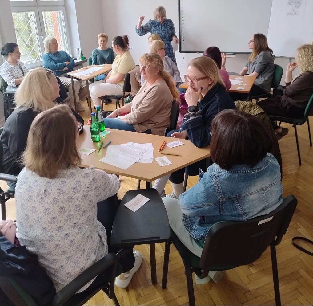 Kobieta prowadzi warsztaty nt. edukacji ekologicznej dla nauczycieli podzielonych na mniejsze grupy
