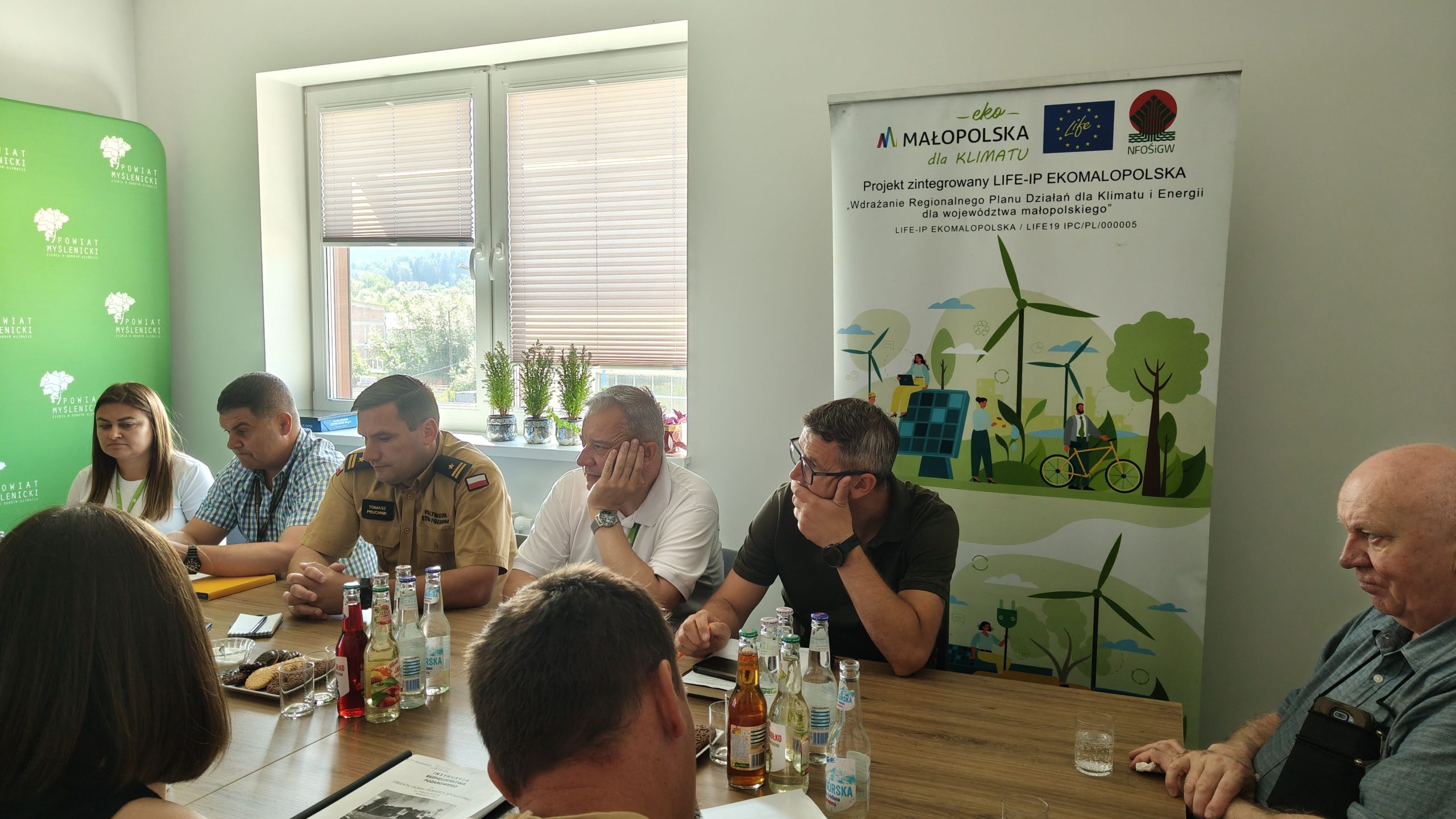 Grupa ludzi siedzi przy stole i rozmawiają