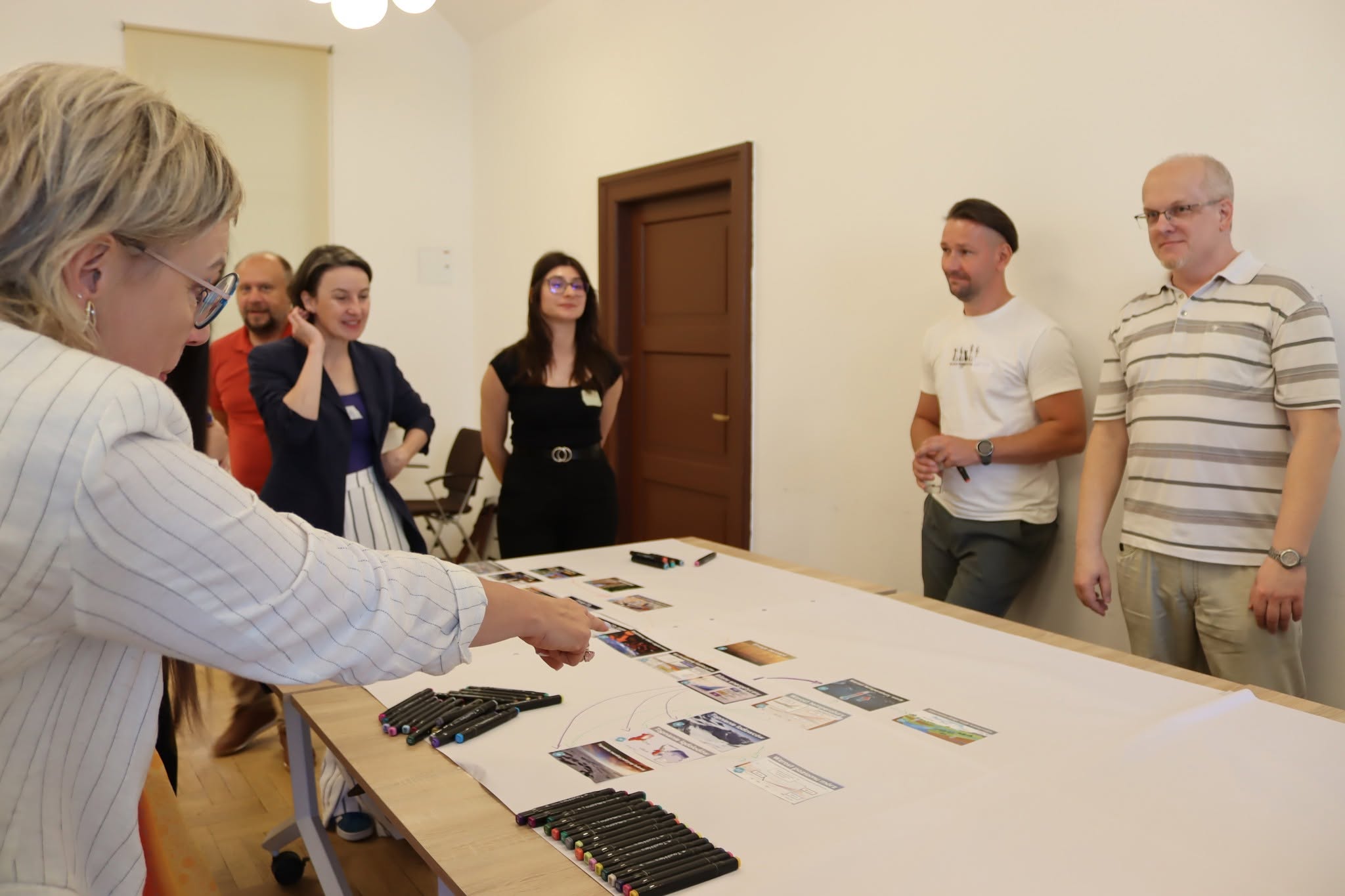 grupa ludzi stoi, a przed nimi stół z kartami do mozaiki klimatycznej
